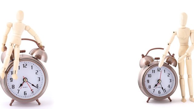 rotating wooden doll and alarm clock on white
