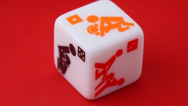 white dice with erotic icons on the sides, rotating on red
