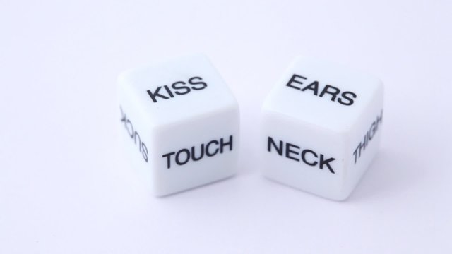 white dice with erotic messages on the sides, rotating on white