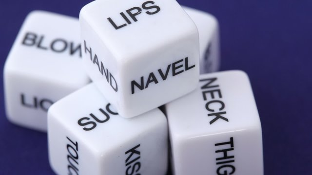white dice with erotic messages on the sides, rotating on blue