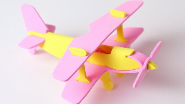 airplane yellow and pink toy rotating on white