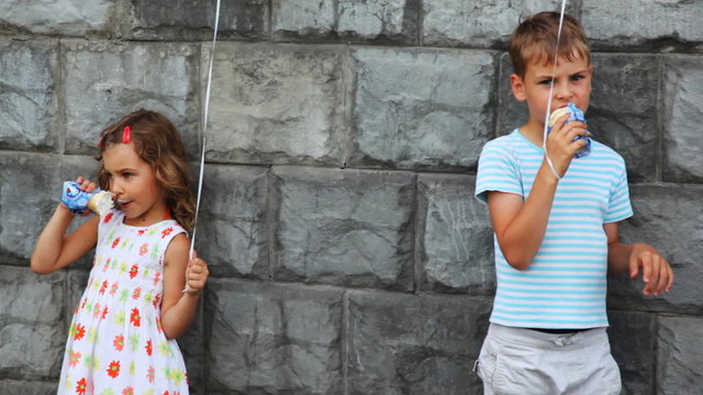 boy and girl standing against wall, eat ice cream