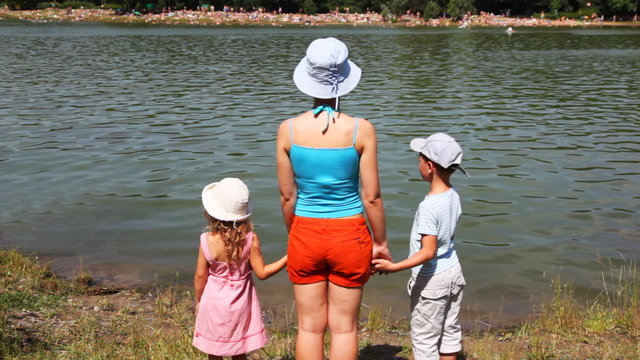 woman with girl and boy standing  toward river, summer