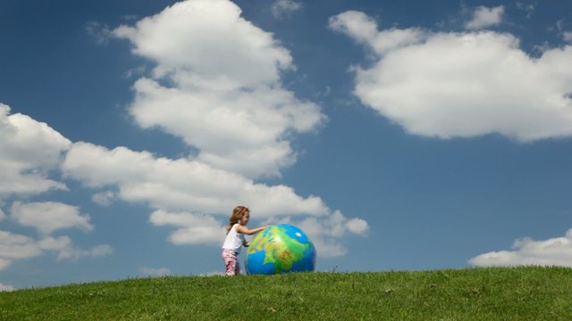 girl trying to catch inflatable Earth ball blown by wind