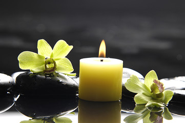 aromatherapy candle and zen stones with green orchid reflection