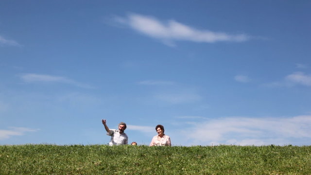 couple and granddaughter go on grass against sky