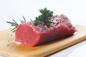 rohes Schweinefilet mit Kräutern auf Holzbrett / raw pork with h