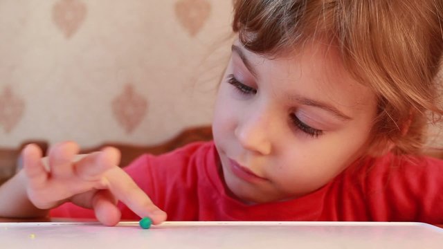 beautiful girl rolling plasticine ball on wooden table