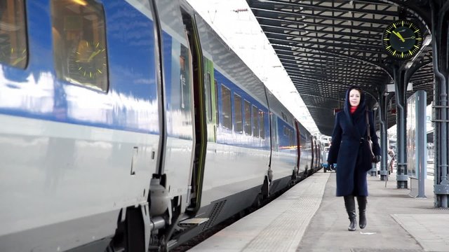 woman at the train station is on  platform along the train