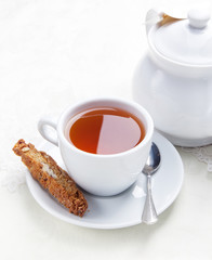 Cup of tea with cookie near the teapot  on white table