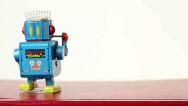 closeup of blue clockwork robot make steps on table, beats drum