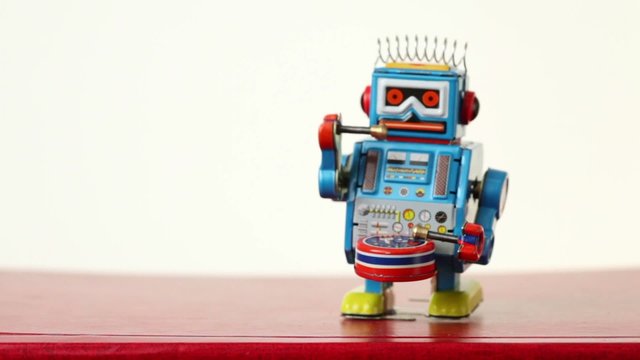 closeup of blue clockwork robot walks on table, beats drum
