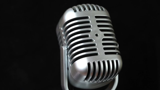 closeup of iron microphone rotates on black backdrop
