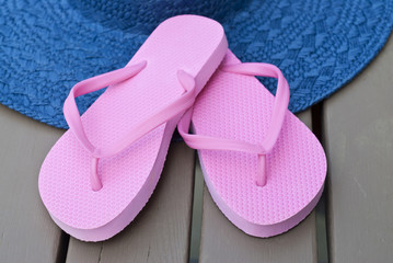 Pink Flip Flop and Blue Straw Hat on a Deck