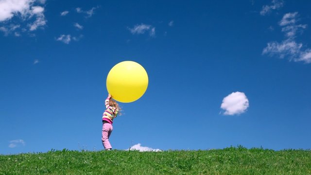 girl stands with yellow bubble on green grass meadow