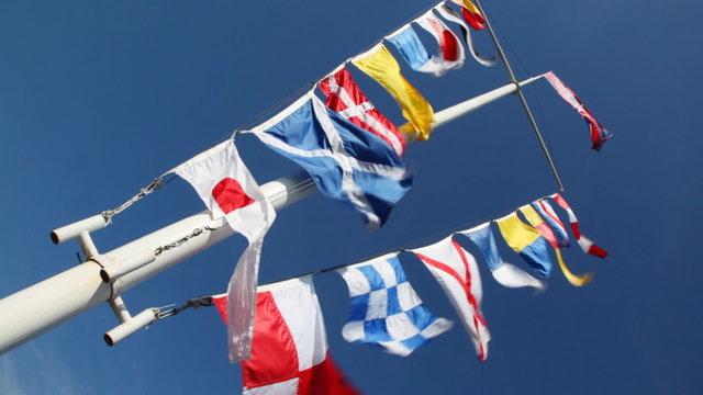 flags of different countries on mast and ropes flapping in wind