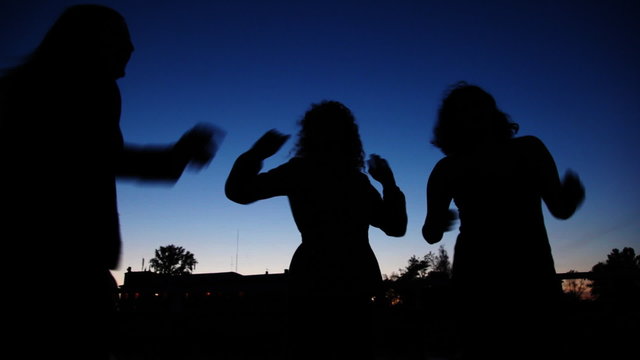 silhouettes of girls dancing on board ship sailing against sky