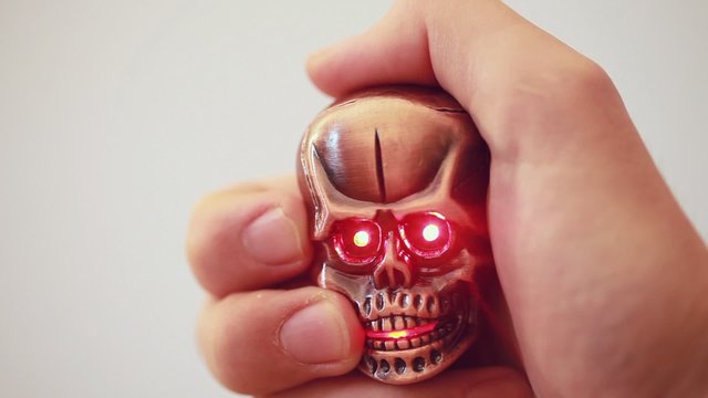 metal lighter in shape of tiny cranium with glow eyes in hand