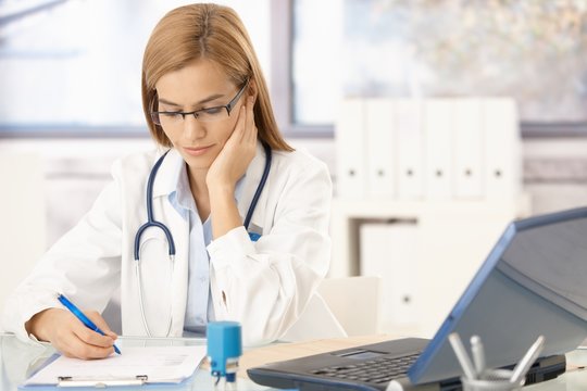Young female doctor sitting at desk working