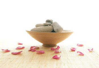 A spa composition of petals and stones on a bamboo carpet