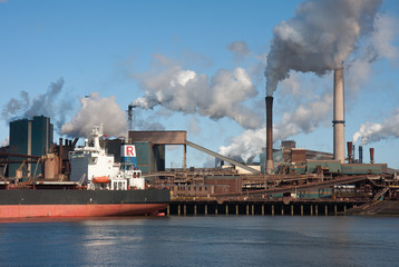 Steel factory with smokestacks and a big cargo ship