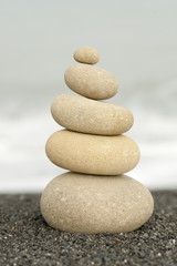 Fototapeta na wymiar pile of balanced rocks on beach against ocean background