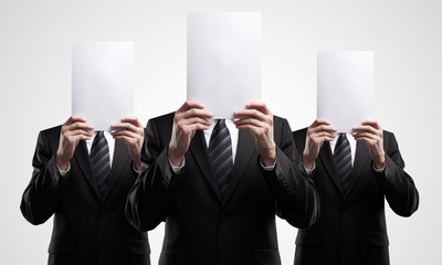 group of business people in dark suits holding a blank signs