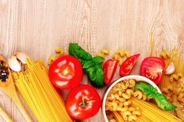 spaghetti with basil leaves, tomatoes and pepper on a yellow bac