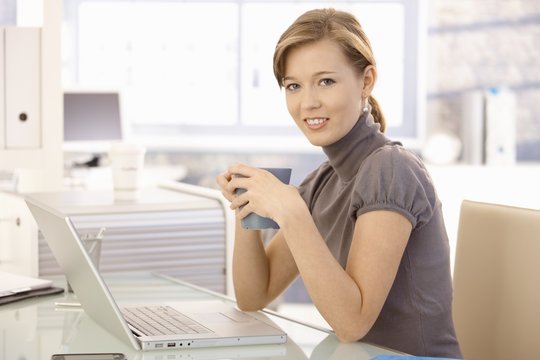 Young businesswoman drinking tea in office