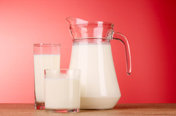Pitcher and Glass with milk on red background