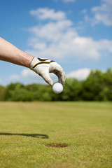 golfer lässt ball ins loch fallen