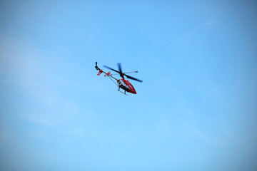 Radio controlled helicopter flying against blue sky.