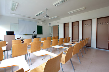 Traditional classroom with desk-chairs, chalkboard and projector
