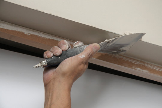 main posant enduit de lissage sur mur