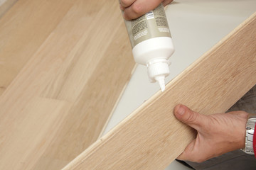 mains posant parquet en chêne semi-massif avec colle