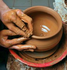 hands of a potter, creating an earthen jar on the circle
