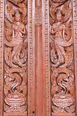 Thai art carving and painting on wooden window of temple