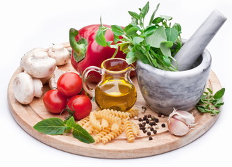 Mortar with pestle, basil herbs, olive oil and vegetables.