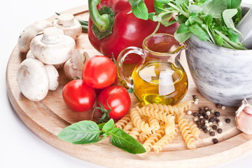Olive oil, herbs and vegetables on desk.