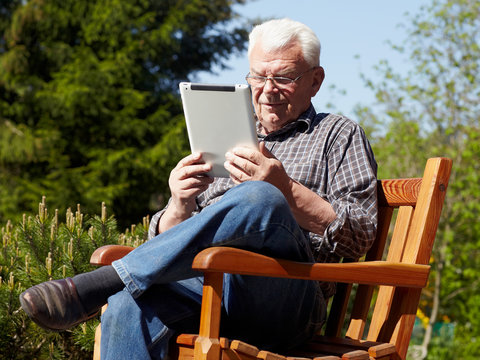 Old handsome grandfather using touchpad e-book reader