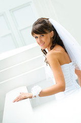 smiles bride in white dress with a veil on white outdoor backgro