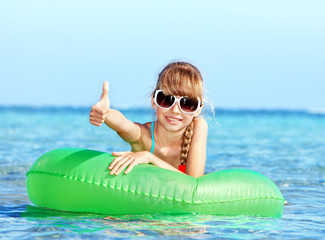 Child sitting on inflatable ring thumb up.