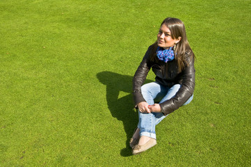Attractive girl sitting on a green lawn. Spring.