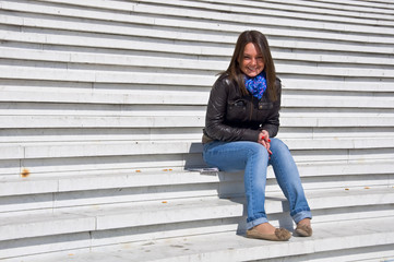 Attractive young woman sitting on the marble steps