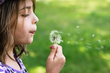 fillette soufflant un pissenlit