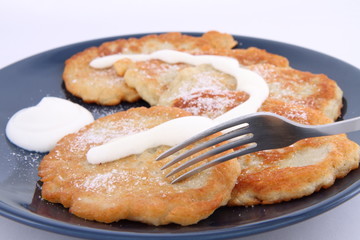 Potato pan cakes with cream and sugar being eaten with a fork