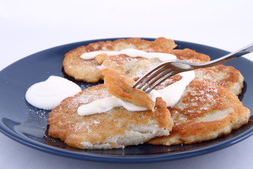 Potato pan cakes with cream and sugar being eaten with a fork