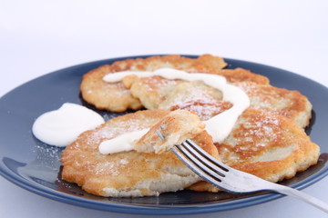 Potato pan cakes with cream and sugar being eaten with a fork