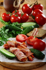 Sausages wrapped in bacon with vegetables and herbs.