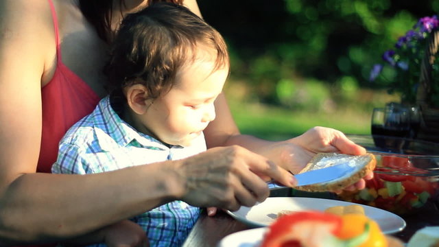 Mother with baby boy eating in the garden